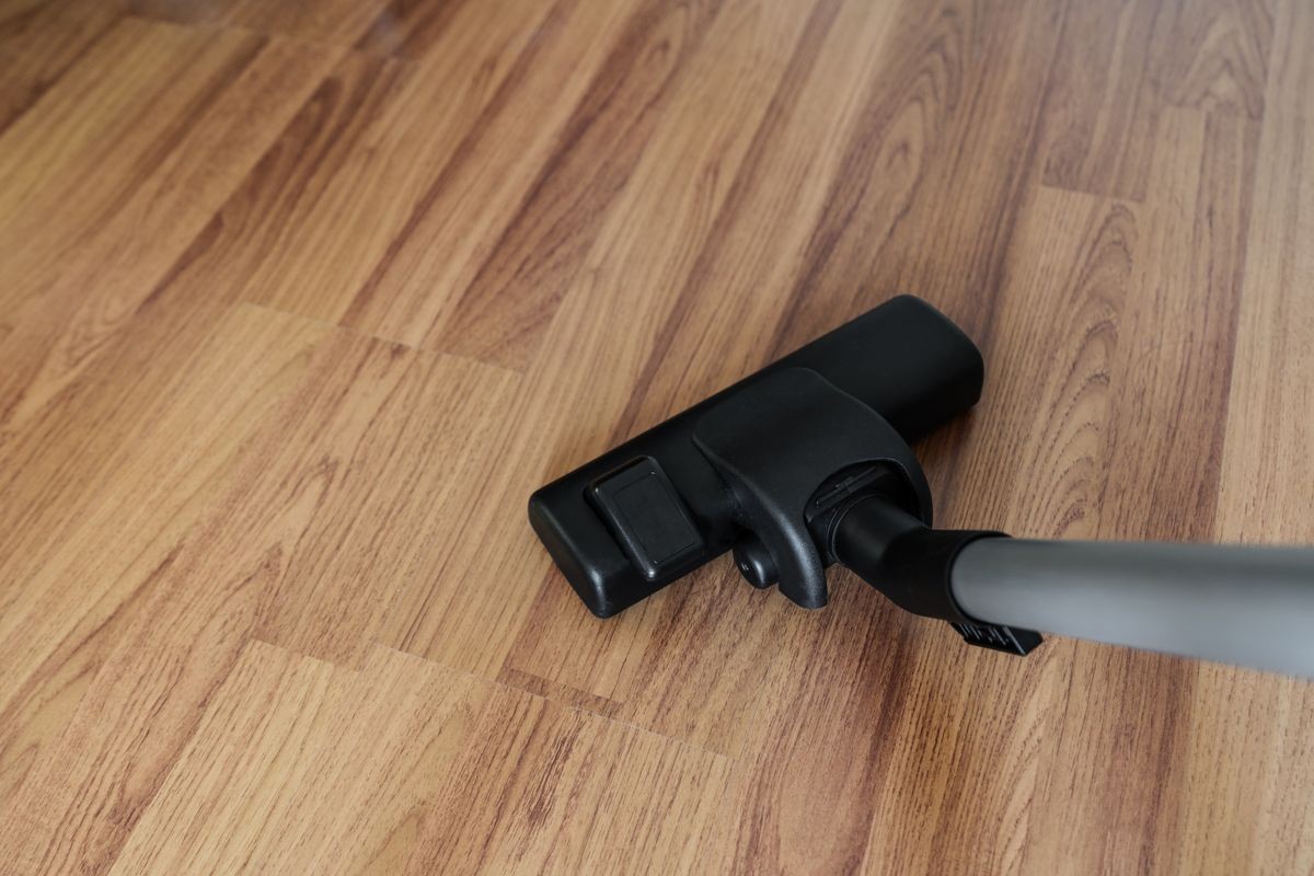 Cleaning laminate wood floor, vacuum cleaner cleaning dust and dirtiness